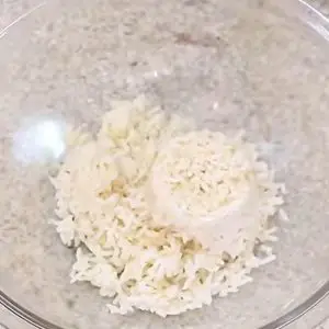Um recipiente redondo de vidro com arroz cozido para preparar o bolinho com sobras de arroz.
