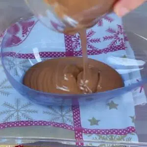 colocando o chocolate derretido dentro da forma de ovo de pascoa
