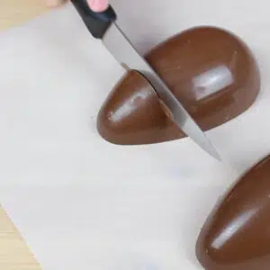 cortando a ponta do ovo de chocolate com uma faca quente