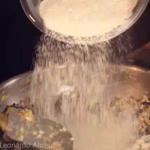 adicionando farinha de mandioca no feijao tropeiro