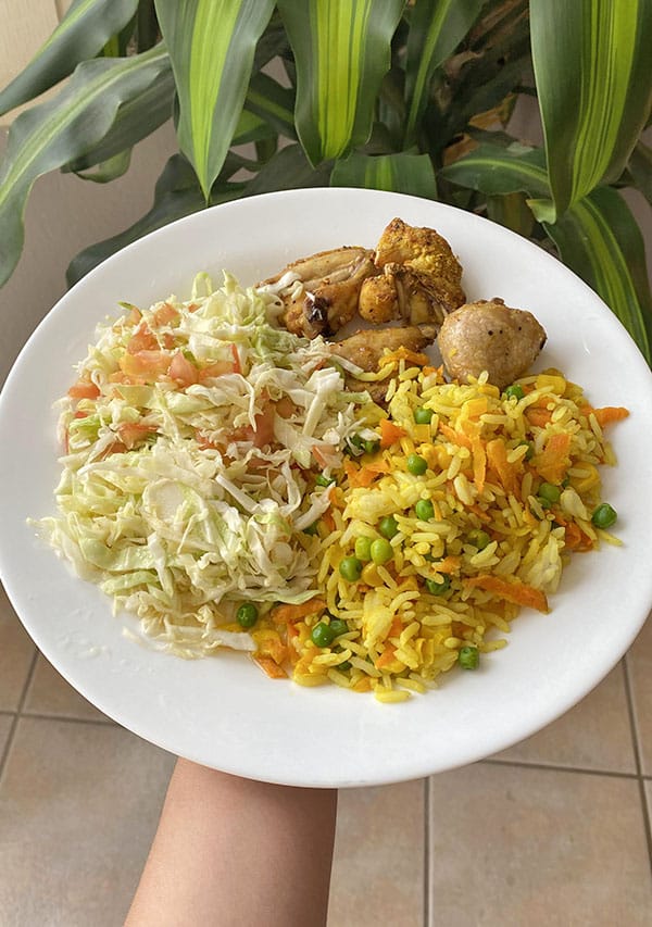 prato com salada de repolho, arroz com ervilha e milho e coxa e sobrecoxa picada